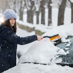 凍った車のフロントガラスを取り除く女性