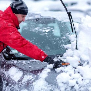 車に積もった雪かきをする男性